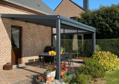 Une table de jardin sur une terrasse sous une pergola en kit vertu en Belgique