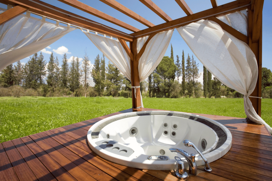 pergola en bois comportant des rideaux, au-dessus d'un jacuzzi